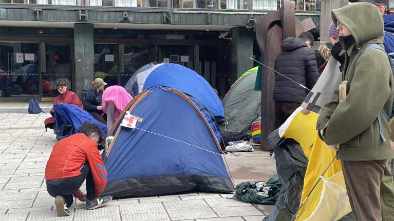 Mielenosoittajat pystyttävät telttoja Helsingin yliopiston edustalla. 